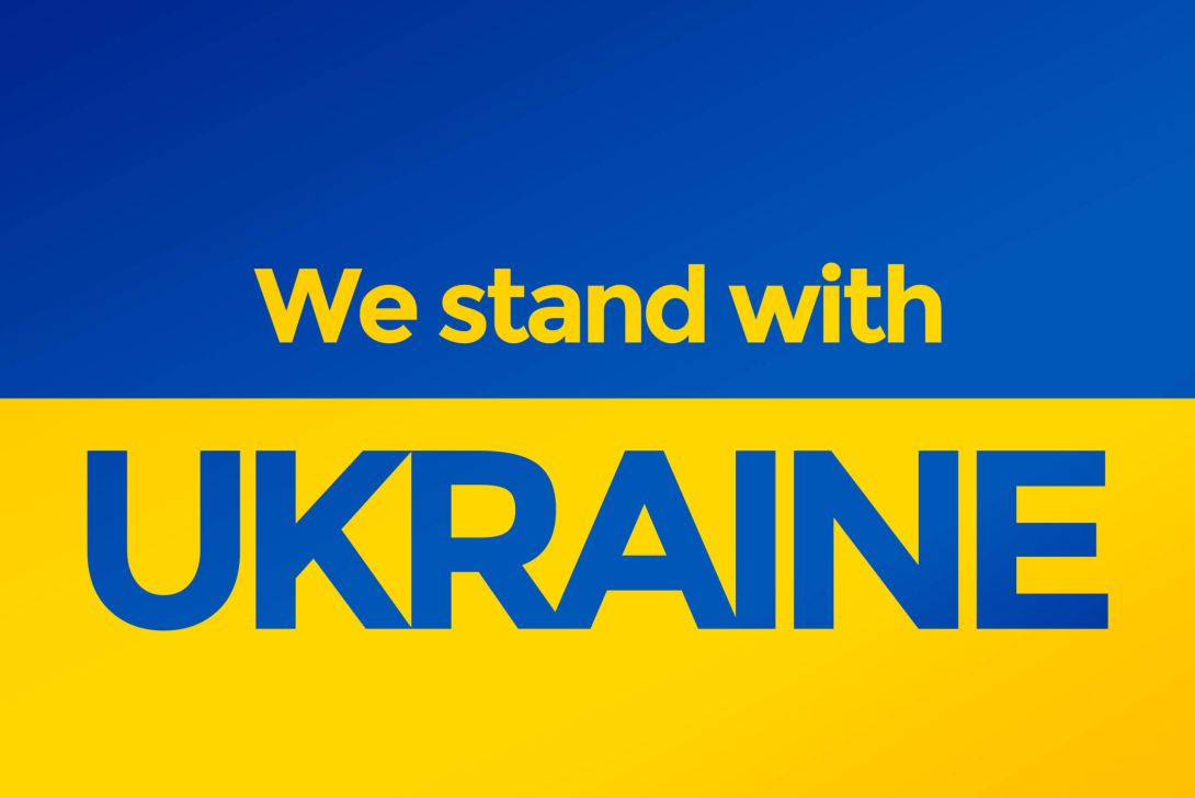 Ein Bild mit den Worten 'We stand with UKRAINE' auf gelbem und blauem Hintergrund, das Unterstützung für die Ukraine ausdrückt.